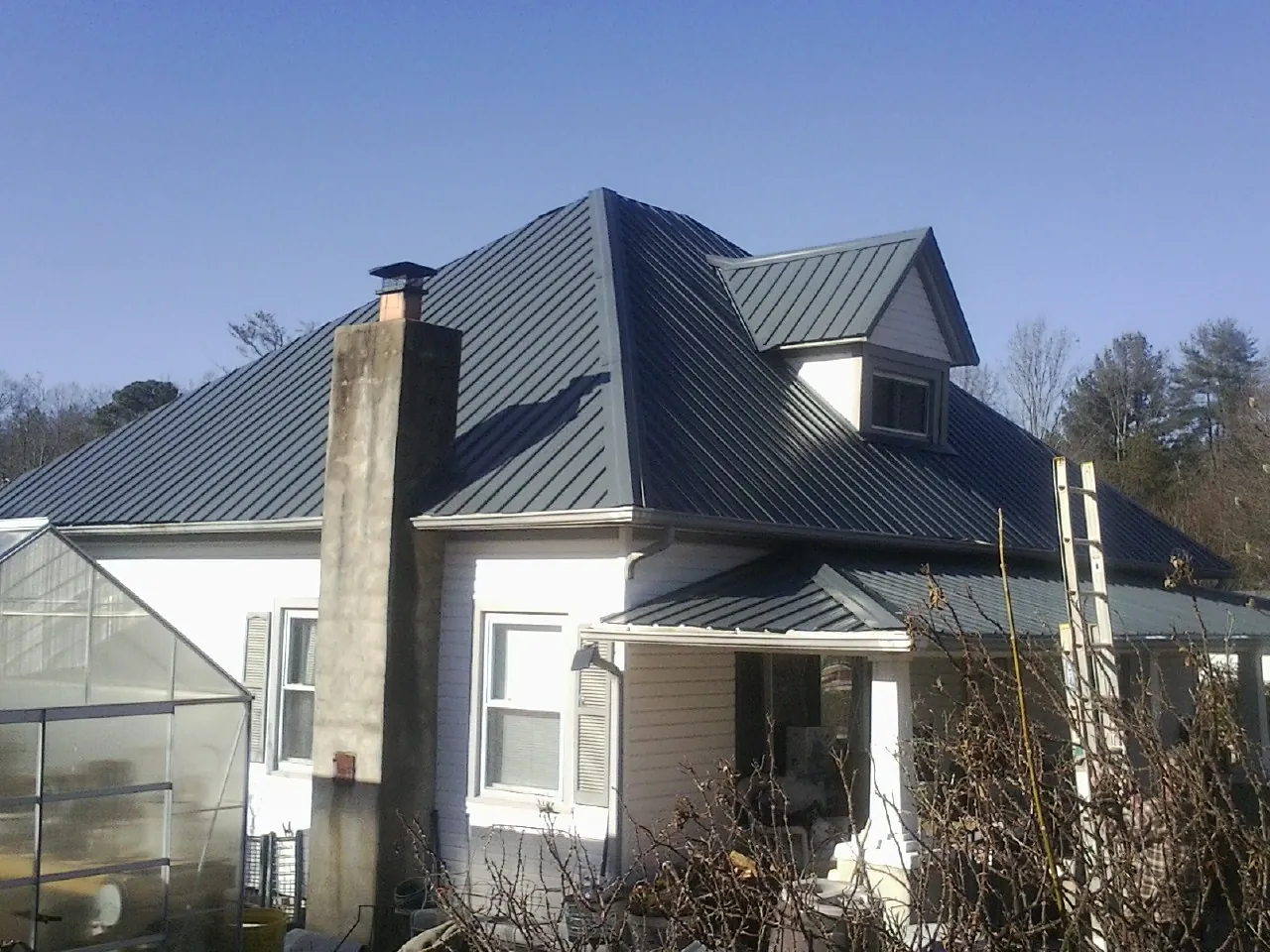 Dark blue standing seam metal roof on a white farmhouse with dormer — Slate & Tile Roof Repair by Roofing Brothers in Grampian