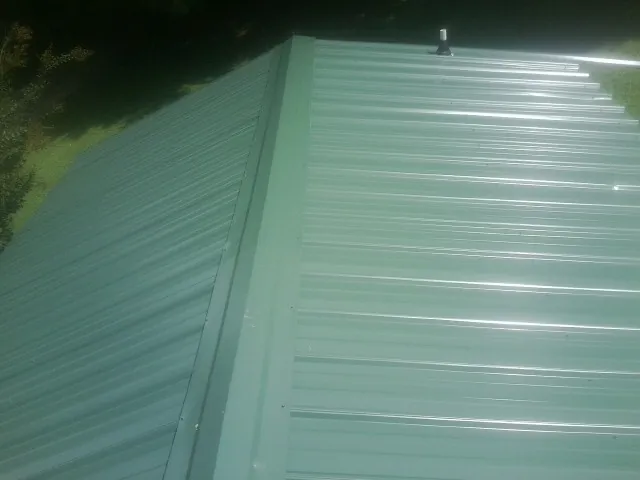 New green metal panels meeting at the ridge of a roof — Flat Roof Repair work by our crew in Grampian