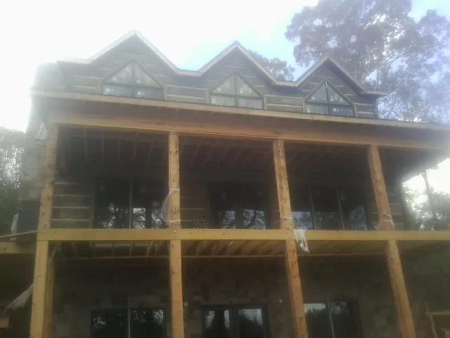 Dormers and porch framing on a large log home under construction — Roof Coating work by our crew in Grampian