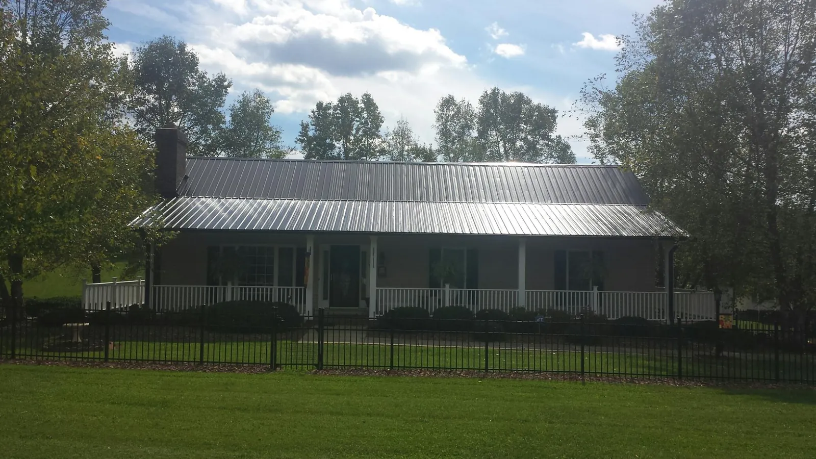 Gray metal roof on a brick ranch with a full width front porch — Gutter Guard Installation work by our crew in Grampian