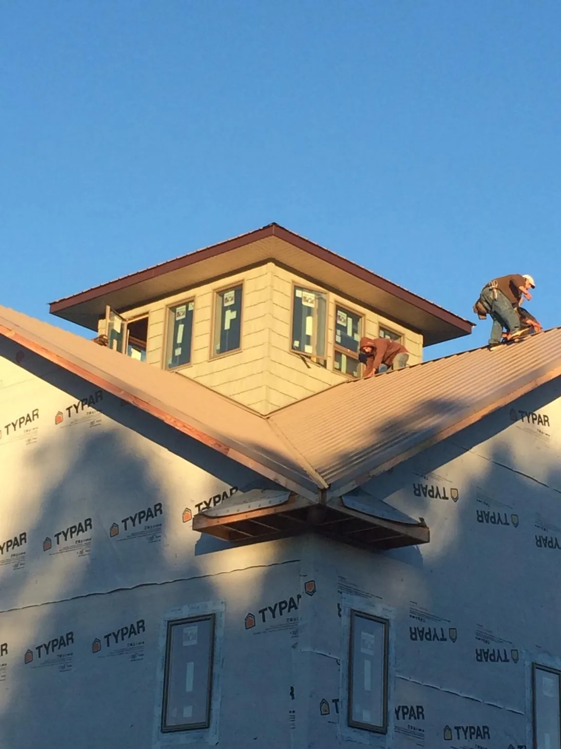 Roofers working around a rooftop cupola on a new metal roof at sunset — Roof Waterproofing in Grampian by Roofing Brothers